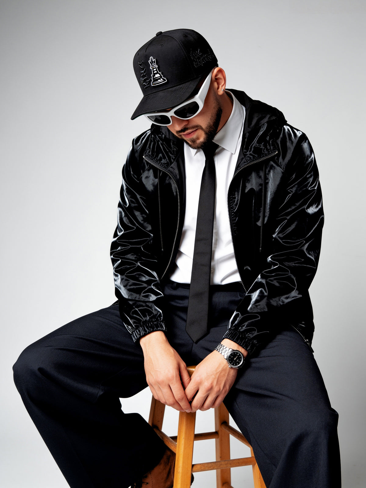 Man in black leather jacket and cap sitting on a stool with 'italiense' branding.